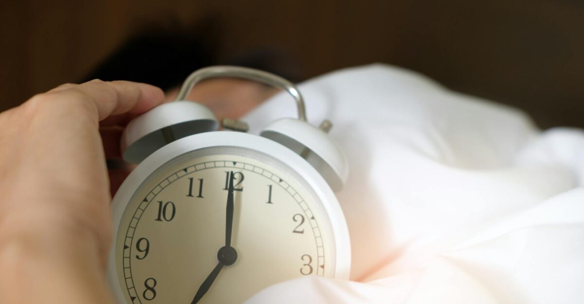 A close-up of a hand reaching for a ringing alarm clock symbolizing waking up in the morning