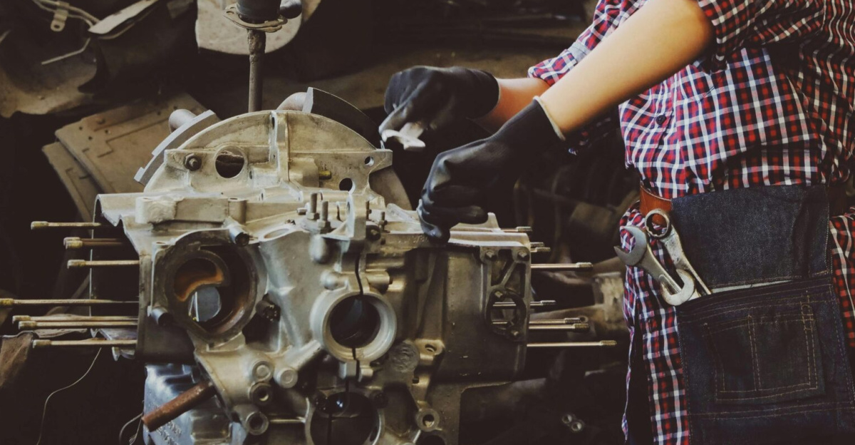 Woman engineer wearing safety gear, working on machine repair in an industrial setting.