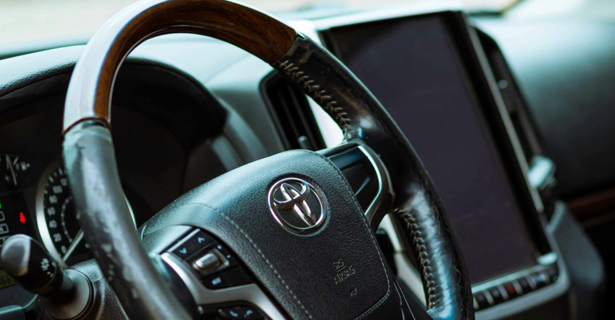 Close-up view of a luxury Toyota car interior featuring a leather steering wheel and modern dashboard controls.