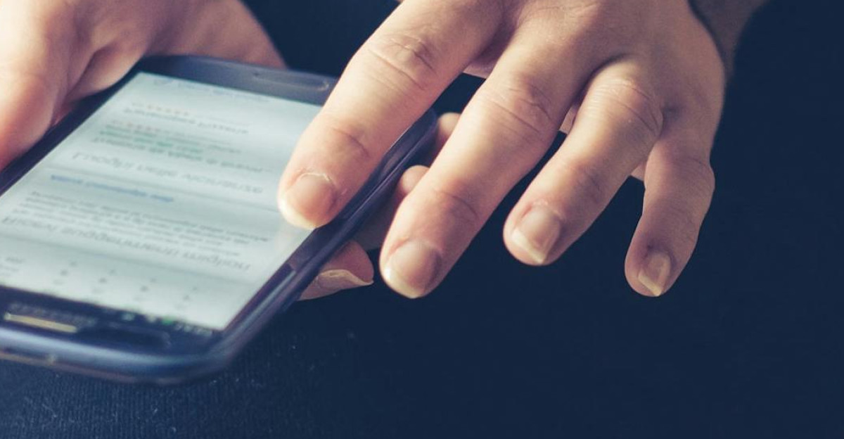Close-up of adult using smartphone indoors browsing web with focus on screen
