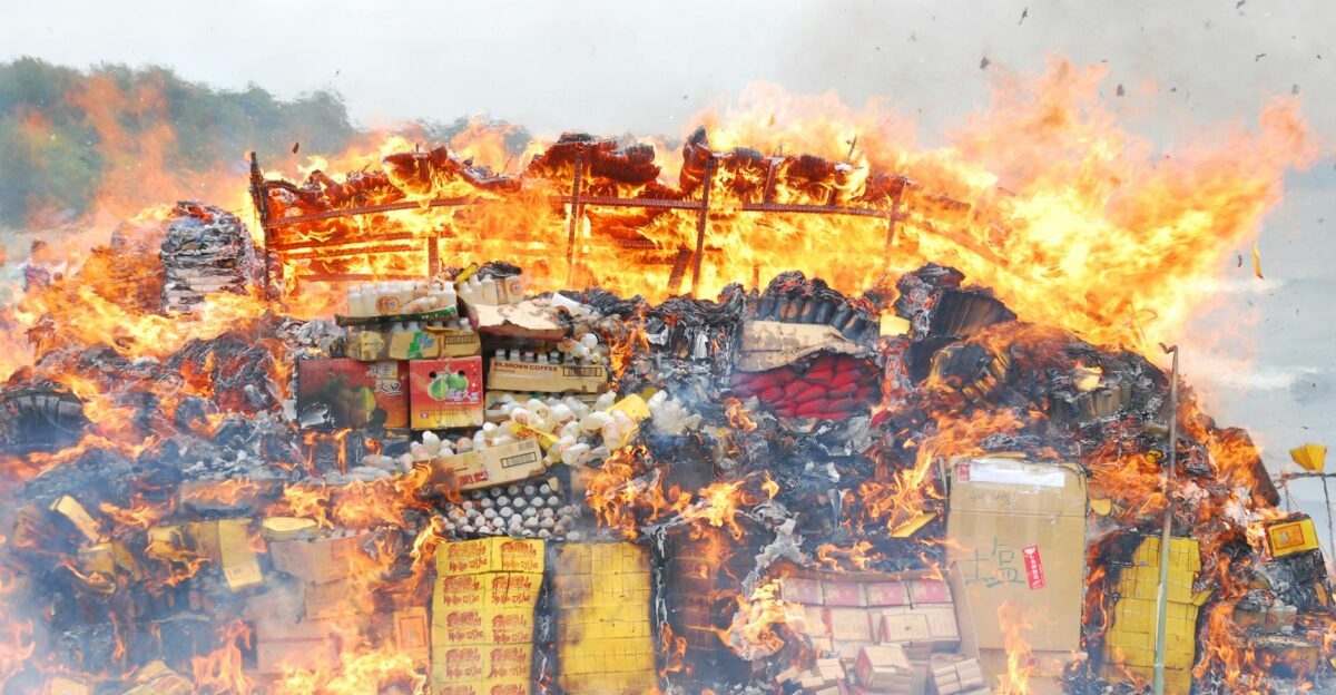 A large bonfire outdoors with assorted boxes and items engulfed in flames