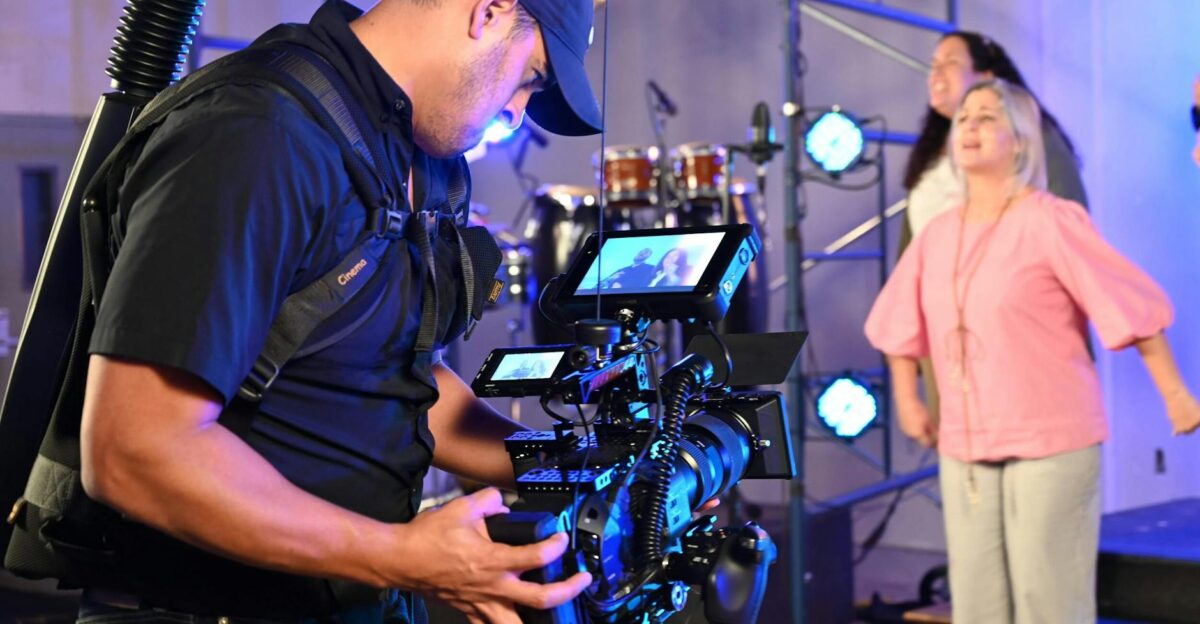 Cameraman capturing live event with professional video equipment inside a vibrant venue