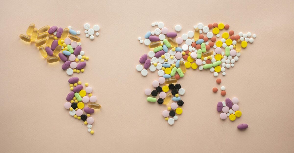 Artistic representation of a world map using multicolored pills on a beige background
