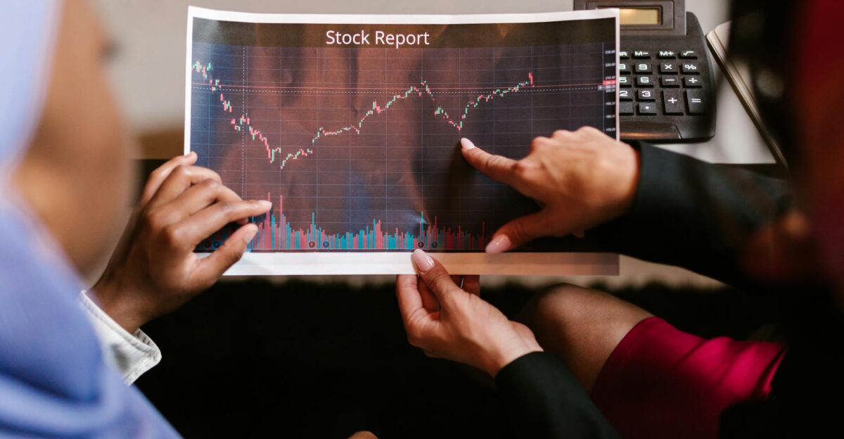 Two professionals discuss a stock report chart in a business meeting analyzing data trends
