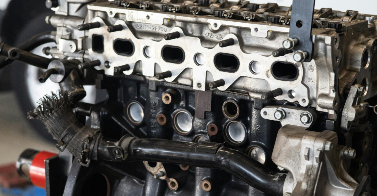 Detailed view of a car engine in an auto repair shop with a blurred vehicle in the background.