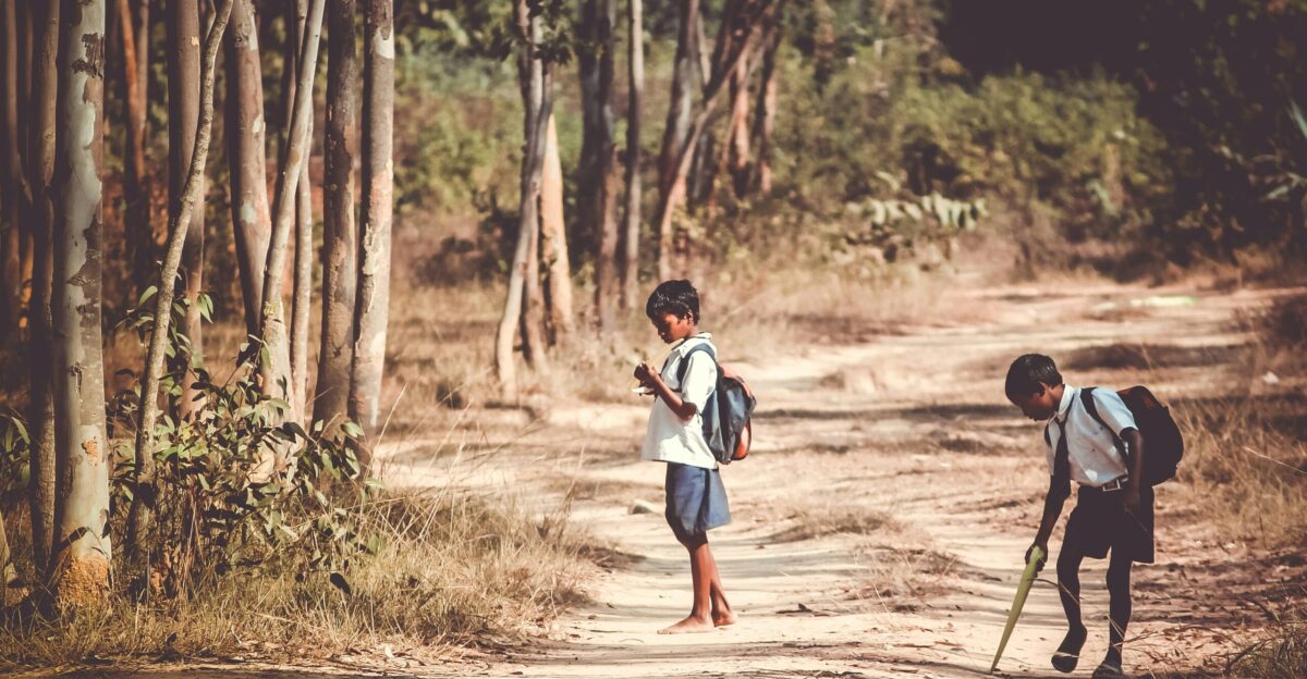 two boys standing on road near tree at daytime