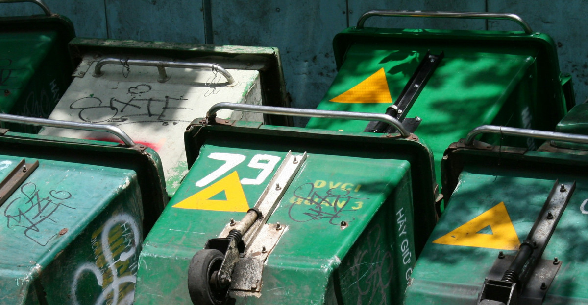 Several green wheeled trash bins are lined up