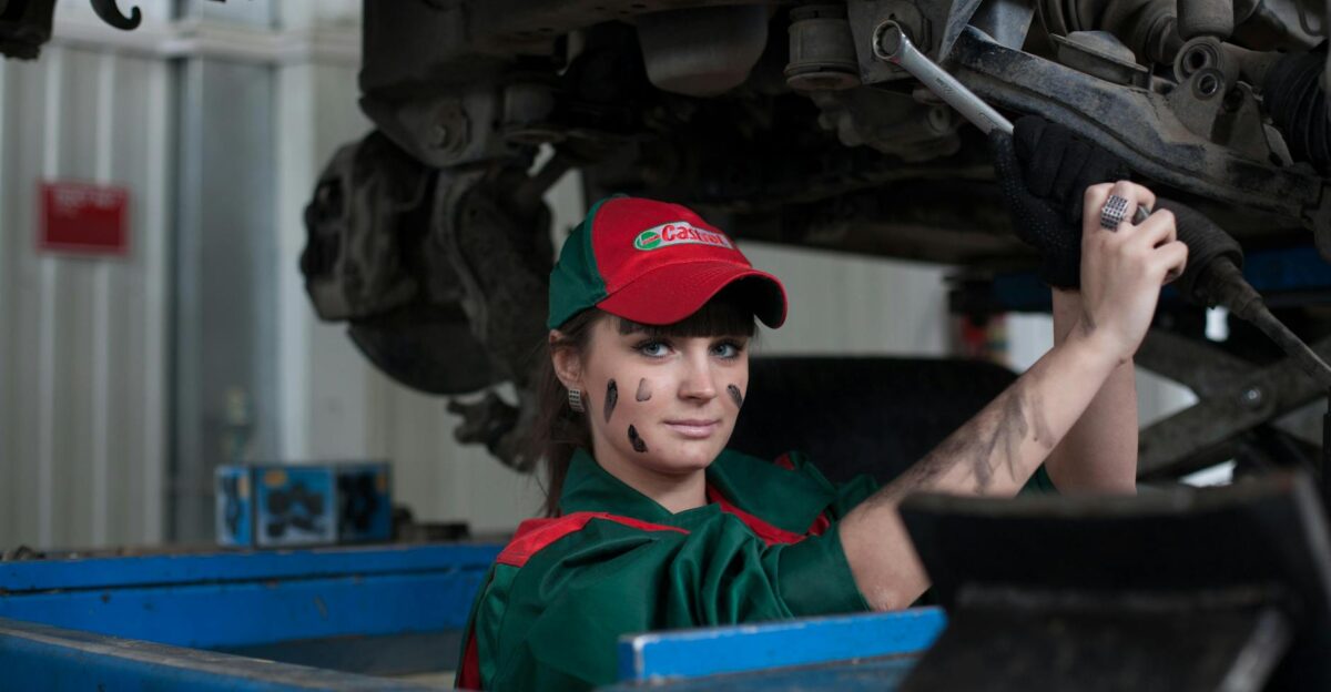 Female mechanic maintaining a car in an auto repair shop showcasing skill and concentration