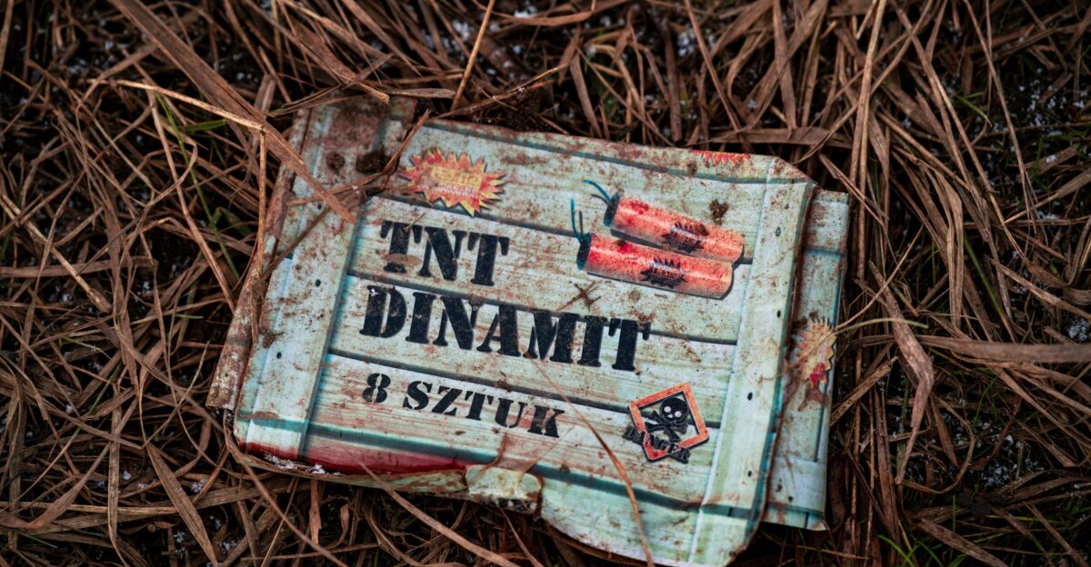 An old TNT box lies on dry grass showcasing rustic and gritty textures outdoors