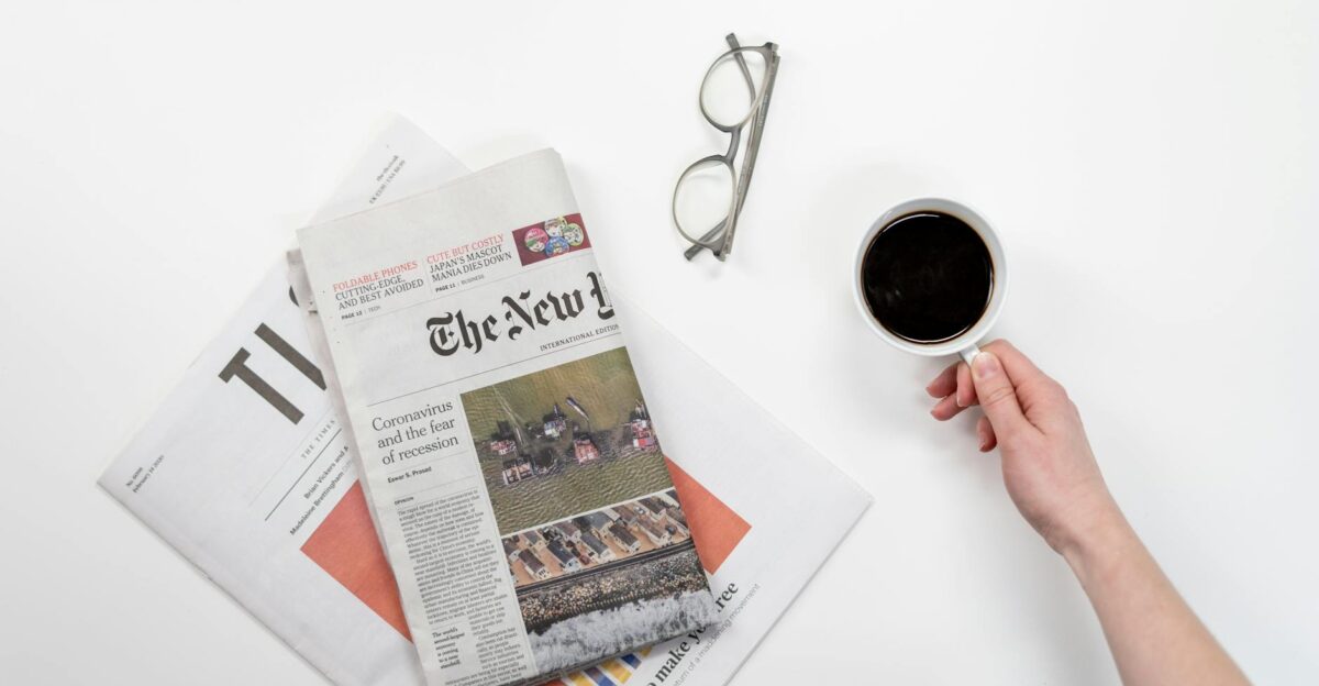 Top view of a coffee cup newspapers and eyeglasses on a clean white desk ideal for a morning routine theme