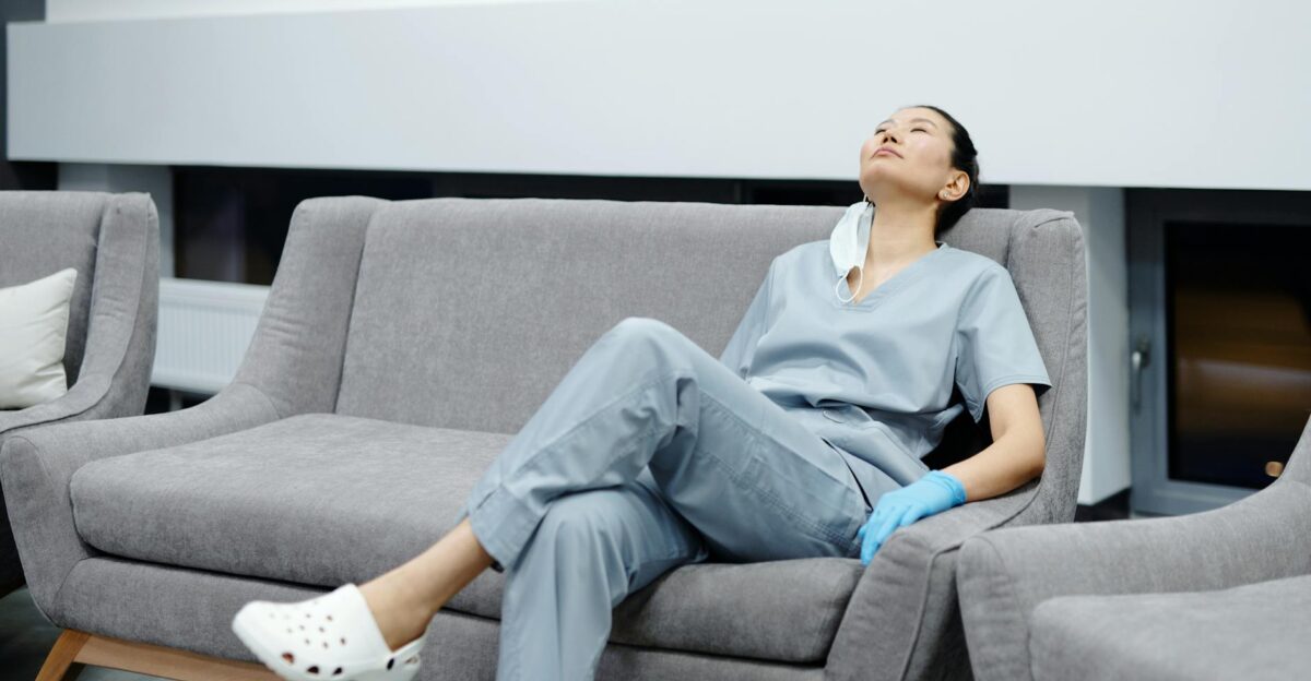 Nurse in scrubs takes a break resting on a comfy hospital couch after a long shift
