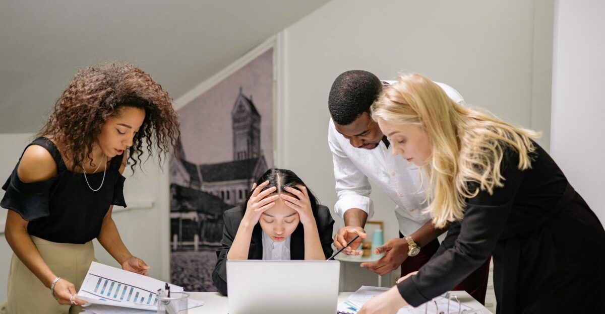 Diverse group of coworkers engaged in a collaborative office meeting discussing around a laptop