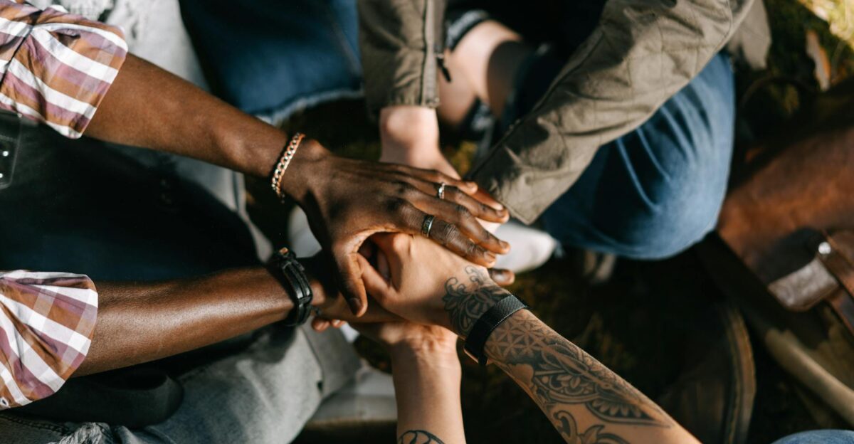 A diverse group of individuals uniting in solidarity with hands stacked together outdoors