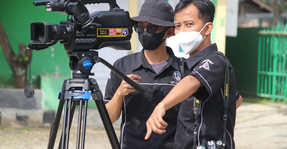 man in black polo shirt wearing white mask holding black camera