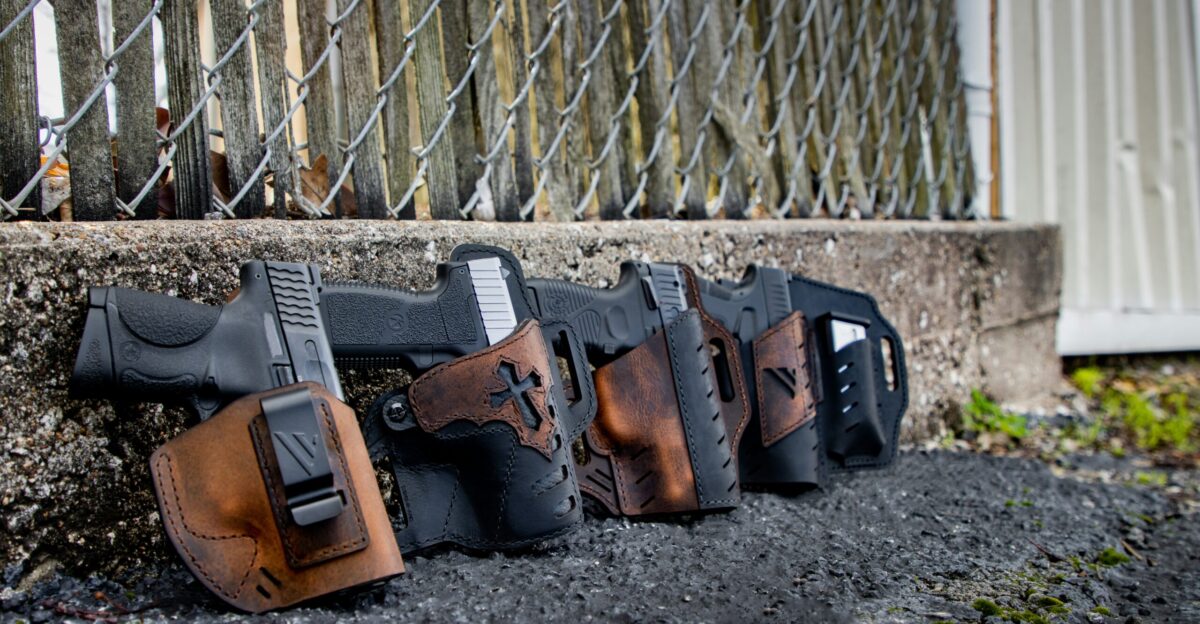 a row of holsters on the ground behind a chain link fence