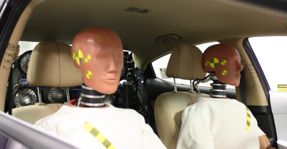 Two Hybrid III crash test dummies positioned in a Hyundai Elantra during vehicle preparation
