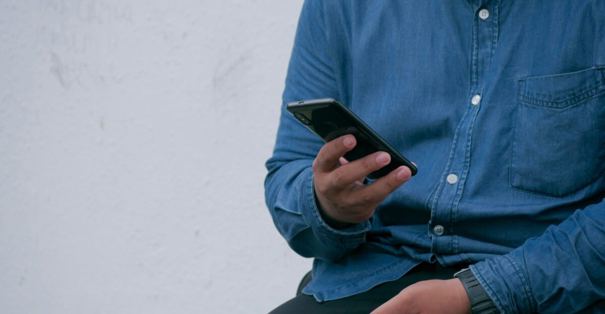person in blue denim jacket holding smarthone