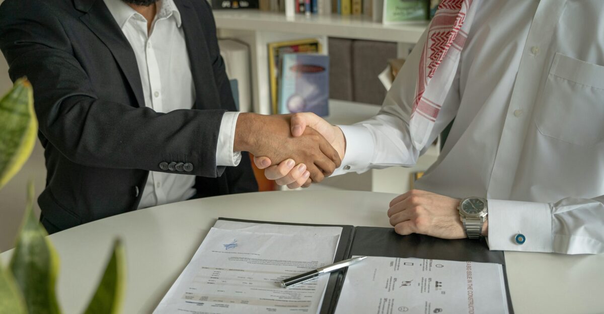 a couple of men shaking hands over a desk